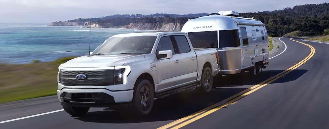 A silver 2022 ford F-150 Lightning is shown towing an airstream.