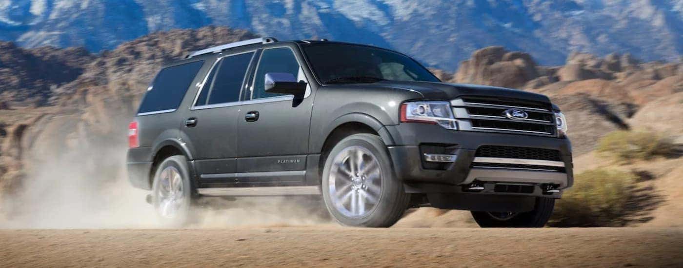 A grey 2018 Ford Expedition is driving in front of distant mountains.