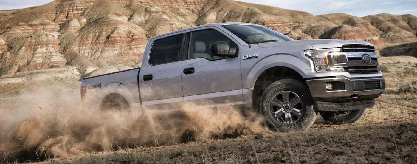 A silver 2018 Ford F-150 XLT is kicking up dust after leaving a used Ford F-150 dealer.