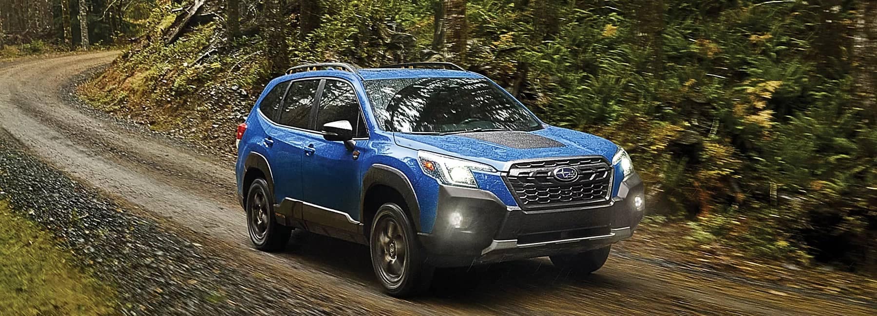 2022 Forester- front 3qview-driving dirt path-navy blue