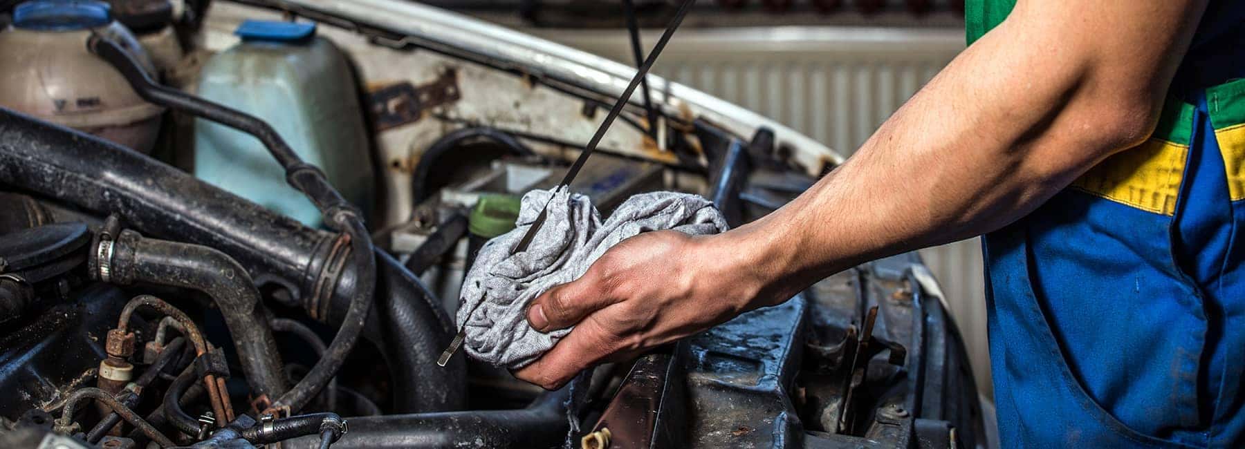 technician wiping off oil dipstick