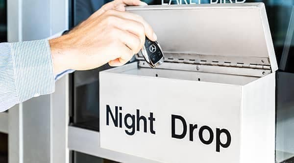 person putting car keys into a box labeled Night Drop