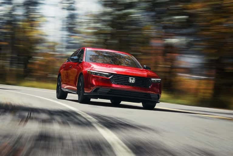 2024-electric-honda-accord-hybrid-bright-red-speeding-along-corner-of-forest-highway