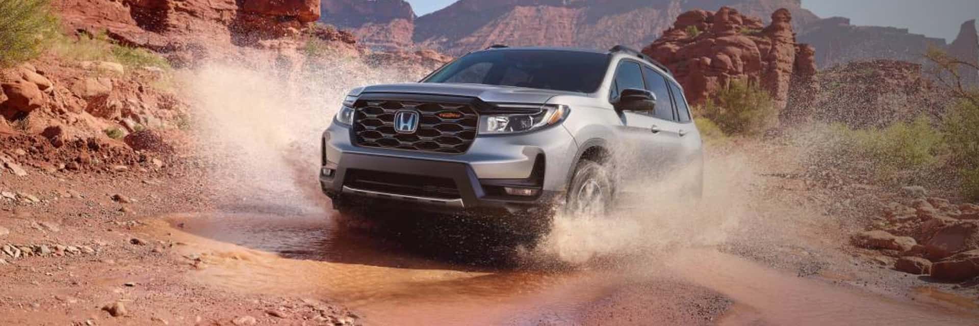 2024-honda-passport-trailsport-splashing-through-a-puddle-in-a-red-sands-desert