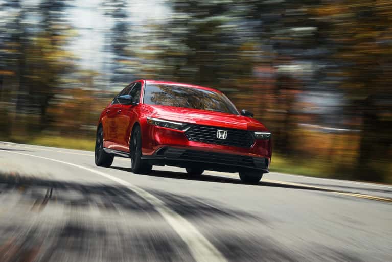 2024-electric-honda-accord-hybrid-bright-red-speeding-along-corner-of-forest-highway
