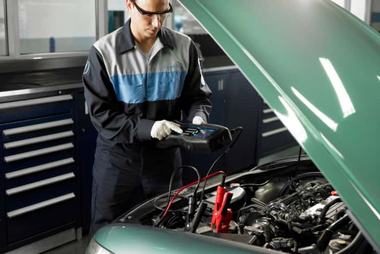 Honda-service-technician-checking-on-the-voltage-level-of-car-engine-mobile