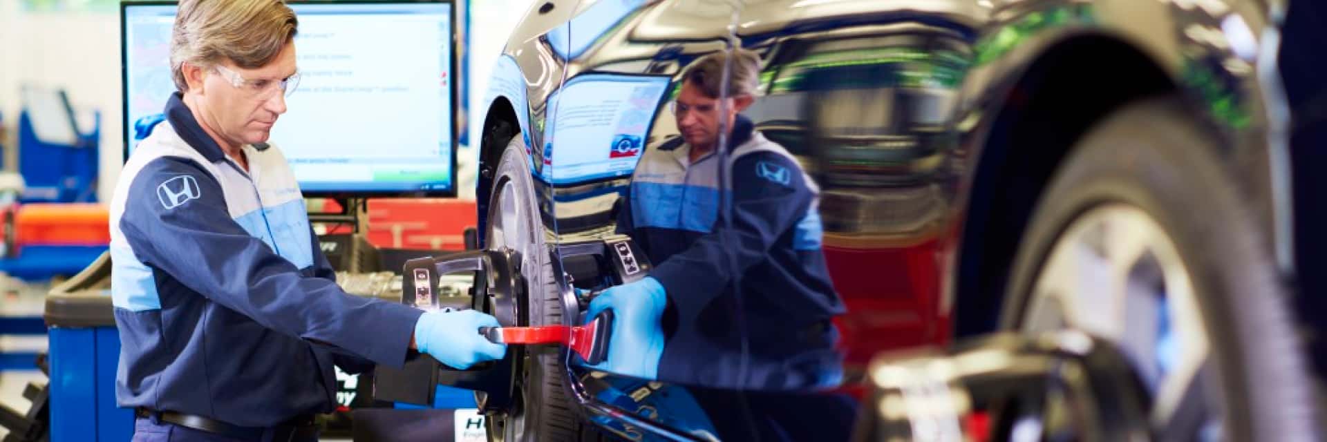 Honda-service-technician-working-on-a-car-tire-with-balancing-tools