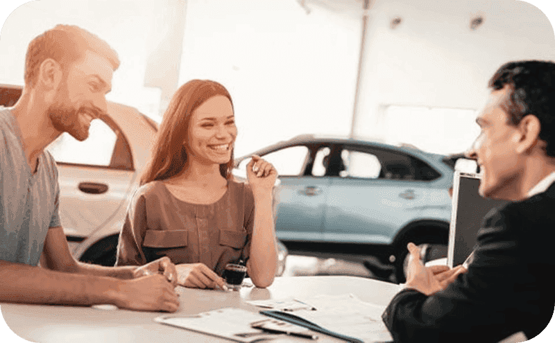 A couple sitting with a dealership salesman