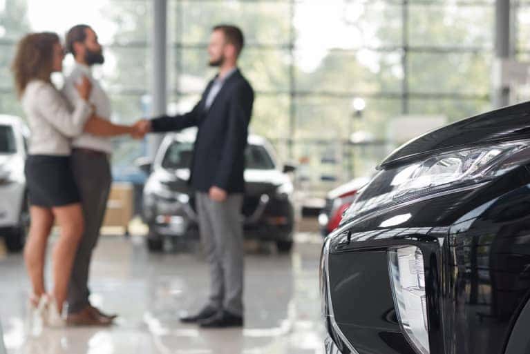 couple-shaking-hands-next-to-vehicle