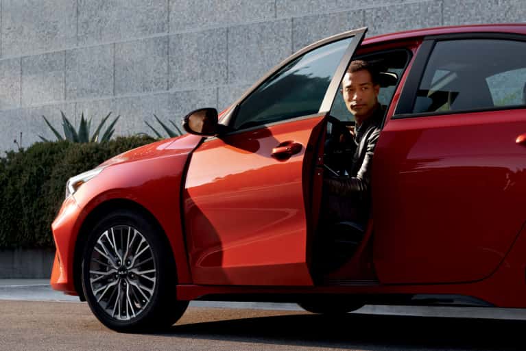 2024 Kia with a man opening the door and looking out 