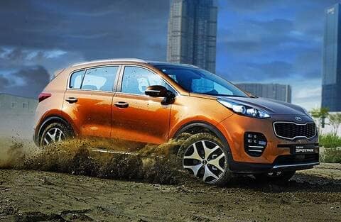 orange Kia Sportage drives through dirt