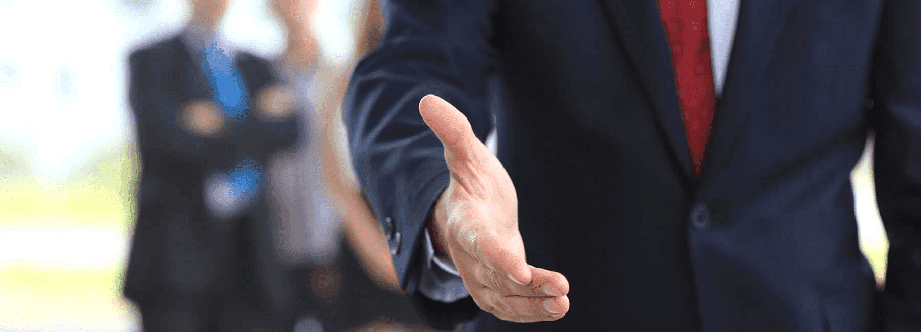 man in suit reaches out shake hands with staff in background