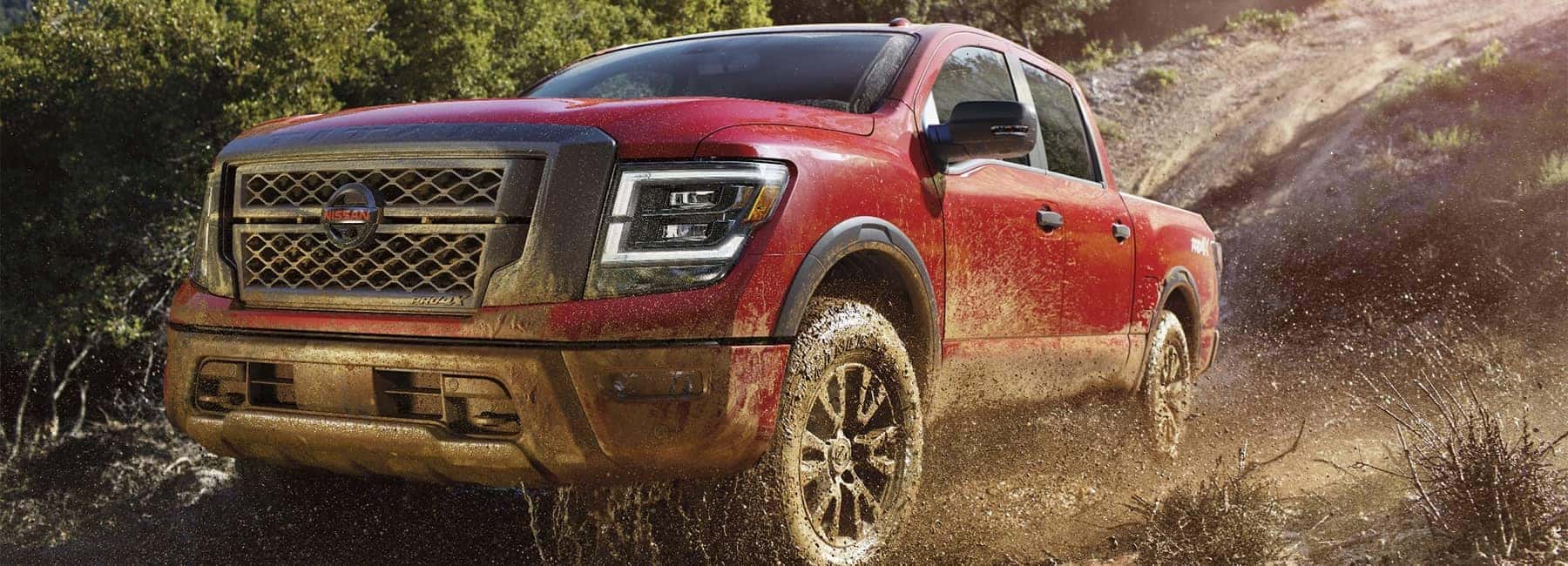 A 2021 Red Nissan Titan truck off roading in dirt