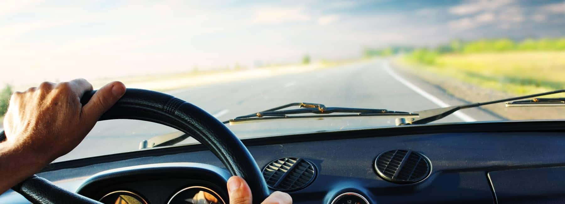hands on steering wheel on an open road