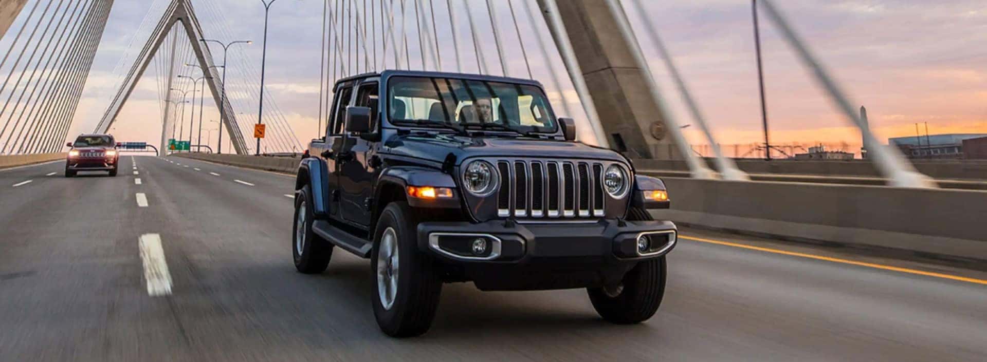 dark Jeep on a bridge driving at sunset