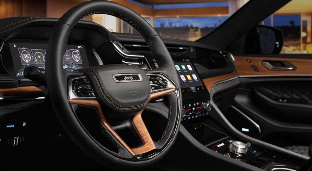A close-up shows the black and brown interior in a 2023 Jeep Grand Cherokee.