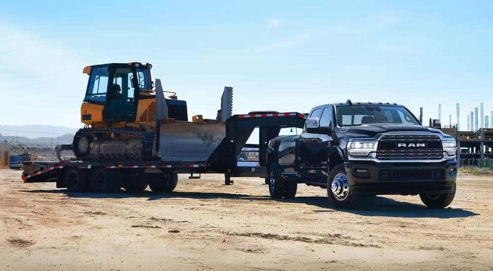 A black 2024 Ram 3500 is shown towing a bulldozer.