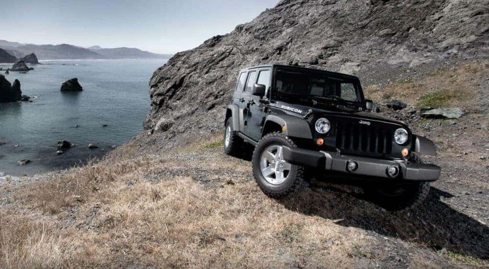 A black 2010 Jeep Wrangler Rubicon Unlimited is shown near the ocean after leaving a used Jeep dealership.