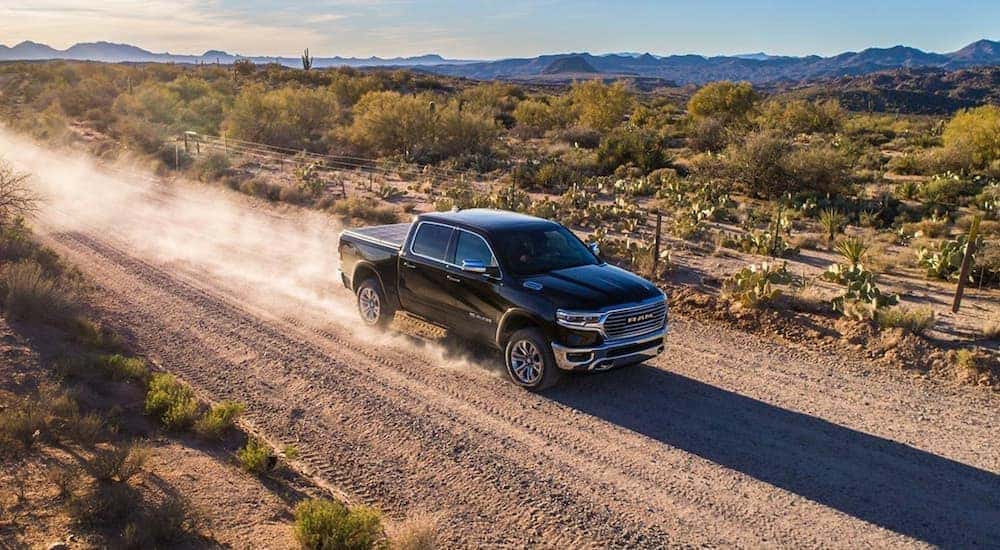A black 2019 Ram 1500 Limited is shown on a dusty trail after leaving a used Ram dealership.