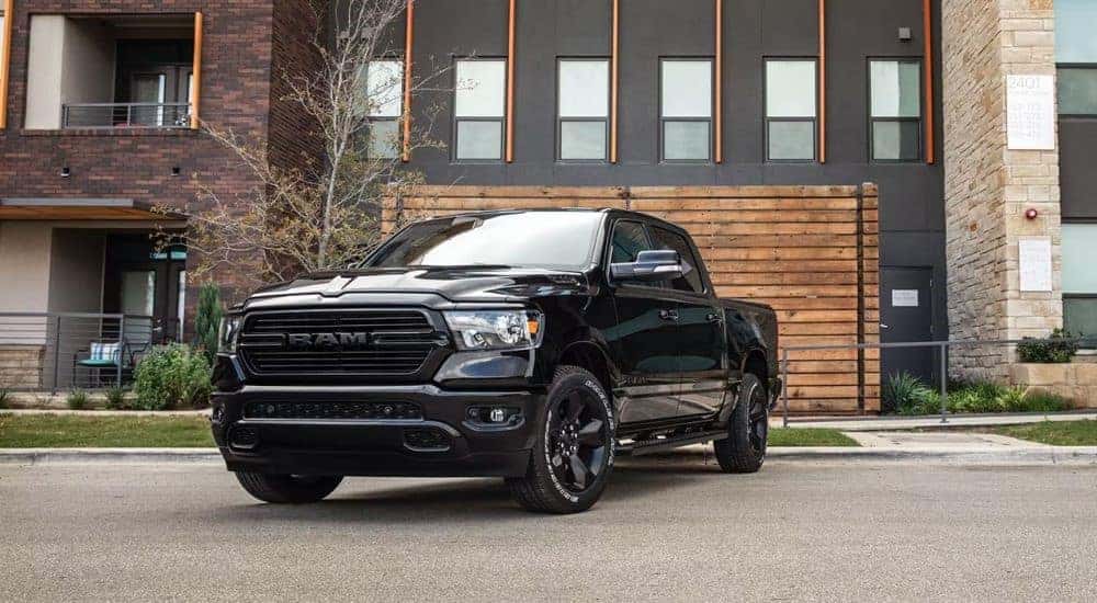 A black 2023 Ram 1500 is shown parked in front of an apartment building.