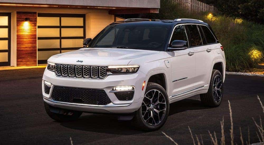 A white 2024 Jeep Grand Cherokee 4xe is shown on a driveway after visiting a Jeep dealer near Mount Holly.