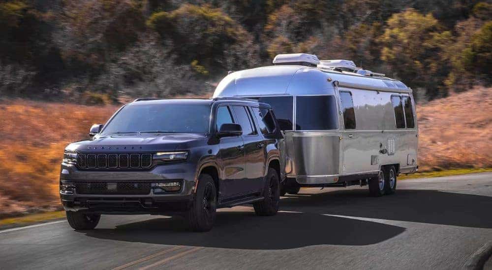 A grey 2024 Jeep Wagoneer is shown towing an Airstream trailer.