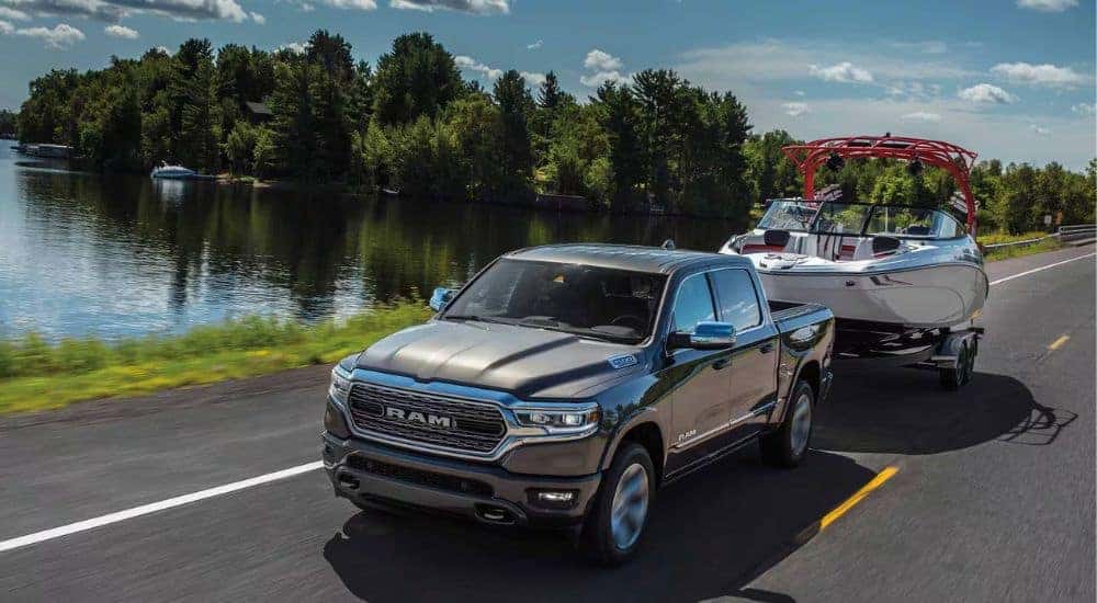 A grey 2024 Ram 1500 is shown towing a boat after visiting a Ram dealer near Mount Holly.