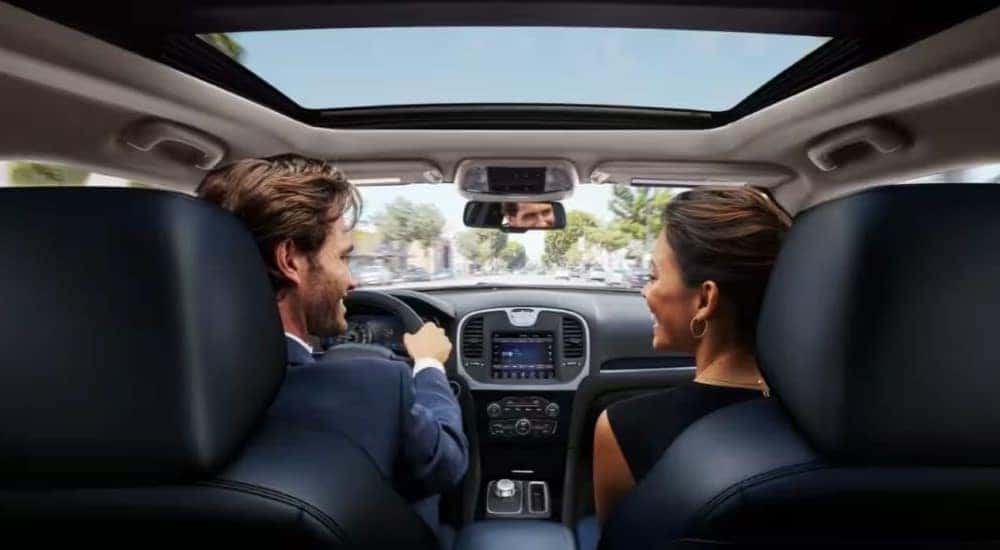 Two people laughing with each other while sitting in the front seat of a 2024 Chrysler 300.