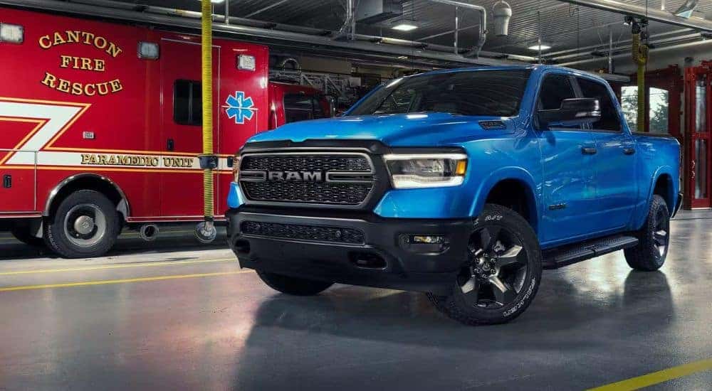 A blue 2023 Ram 1500 Big Horn Built to Serve Edition is shown near an ambulance after leaving a Jeep dealer near Charlotte.