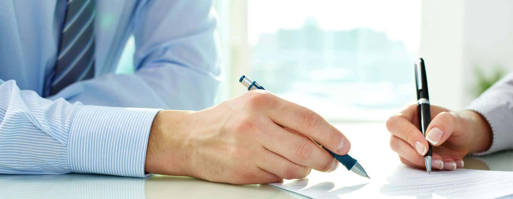 man and woman's hands signing paperwork