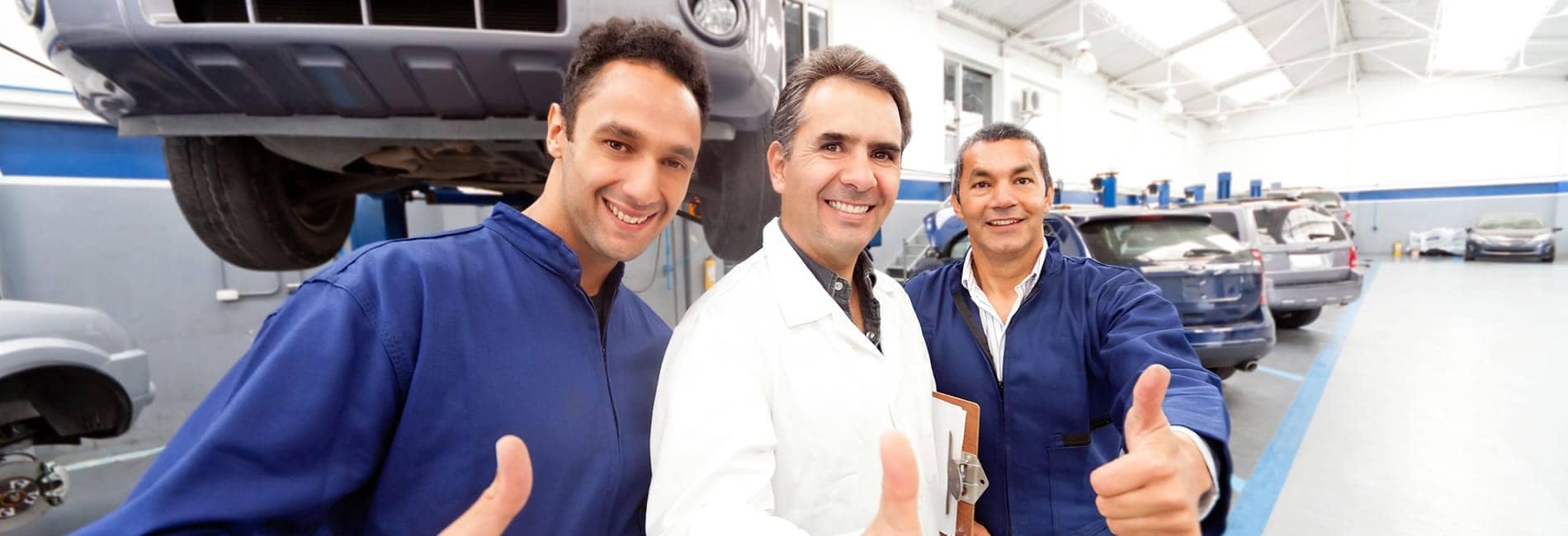 three service technicians giving a thumbs up in body shop