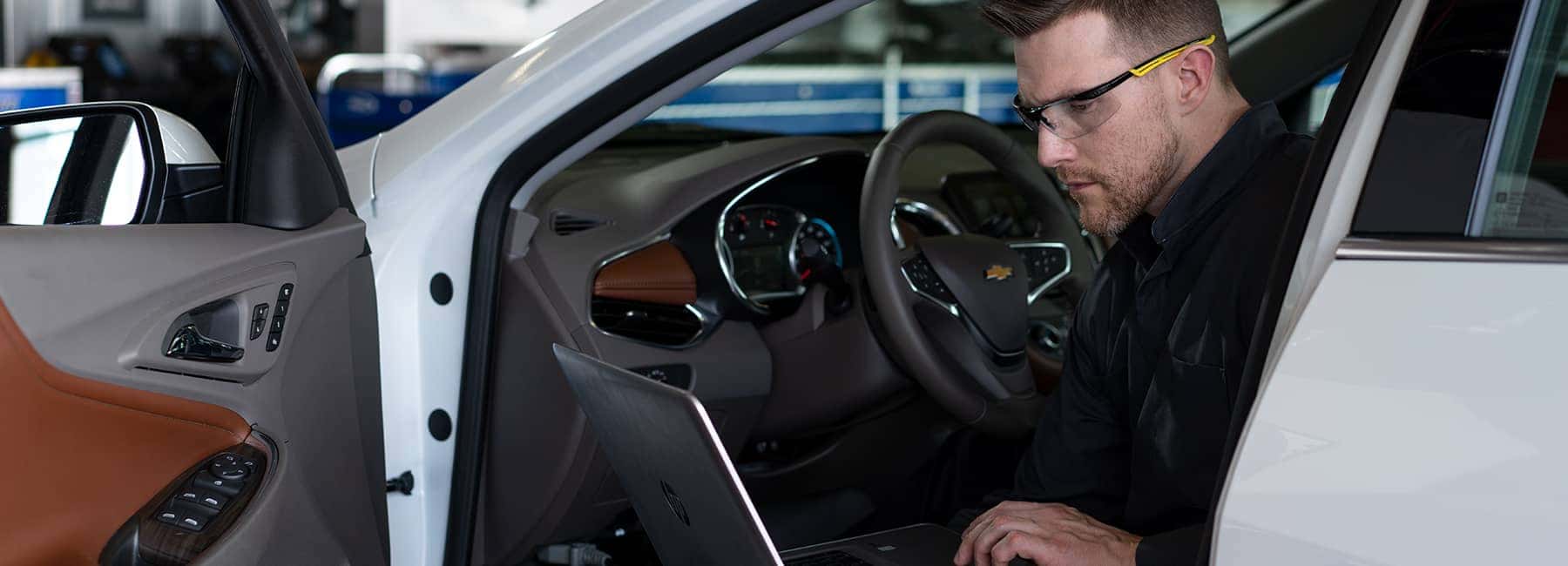 Chevrolet service technician sitting in a car looking at his laptop