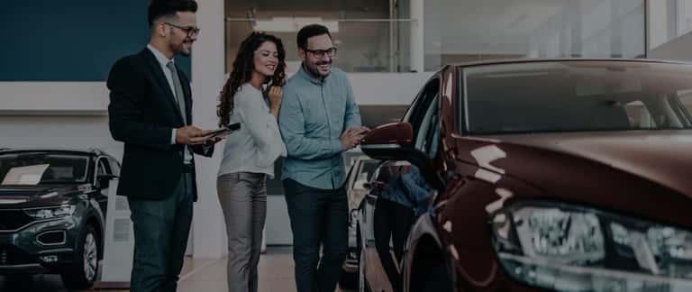 Couple looking at car with salesperson