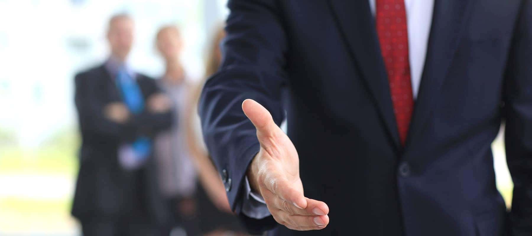 person wearing a suit with an open hand for a hand shake