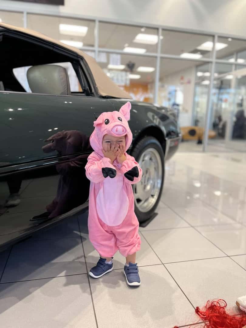 Little girl in pig costume next to a car