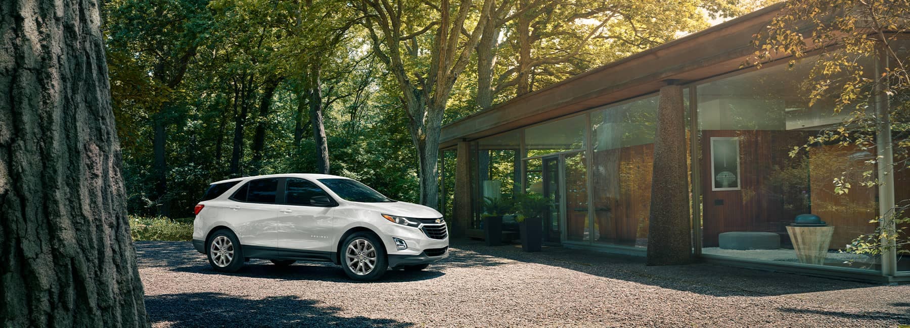 A White 2021 Chevrolet Equinox parked in front of a modern house tucked in the woods