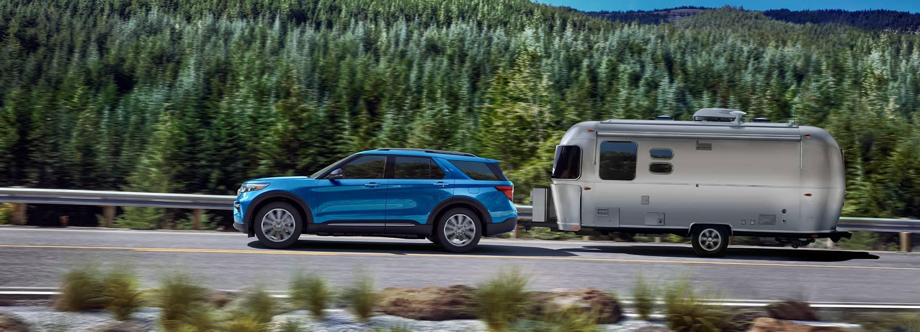 Blue Hybrid 2022 Ford Explorer pulling a camper