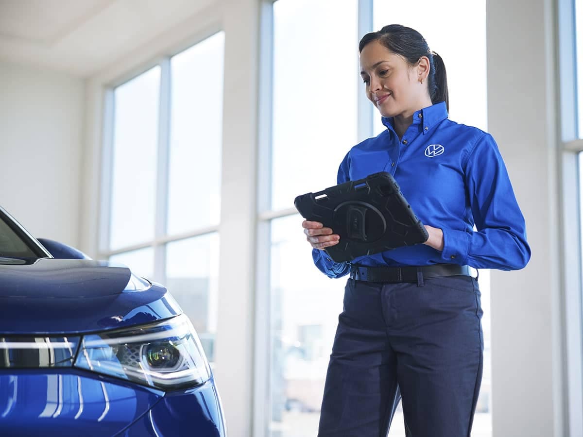 VW technician looking at car with tablet