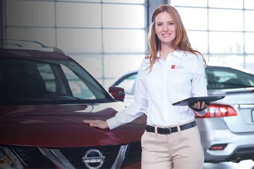 Woman with clipboard standing in front of a Nissan vehicle