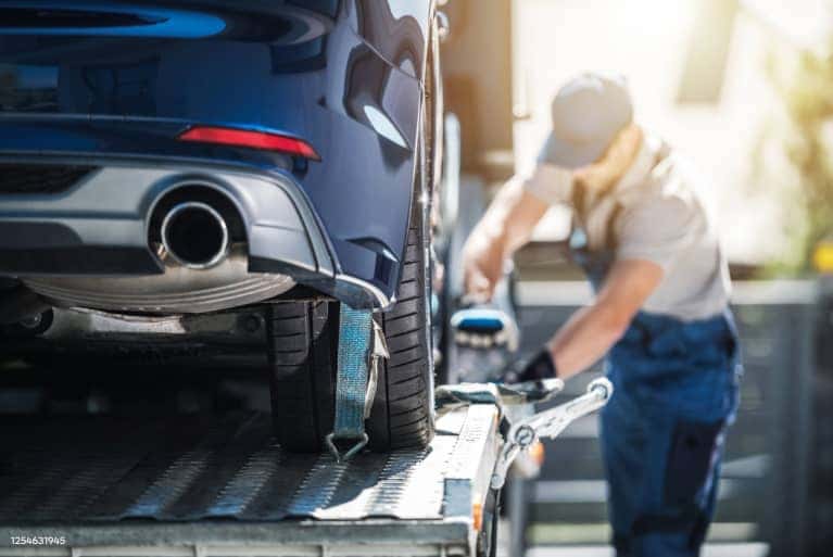 Rear view of a car being loaded onto a flat bed truck