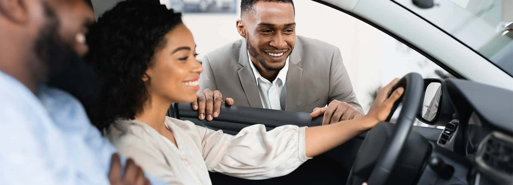 Happy customers review the interior dashboard and settings for their new car
