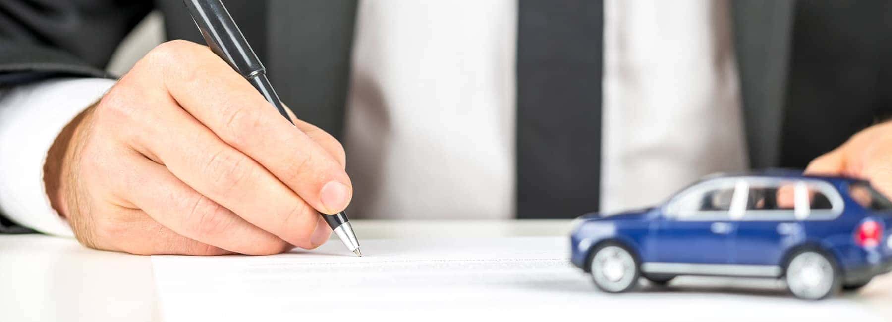 Man Signing Document with Blue Toy Car
