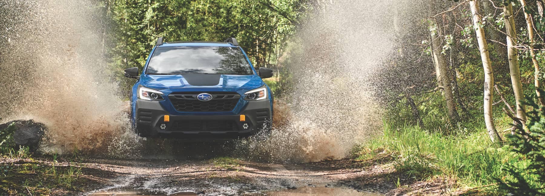 2022 Subaru Outback- front view- driving trough large puddle in forest-spalshes-blue_black_
