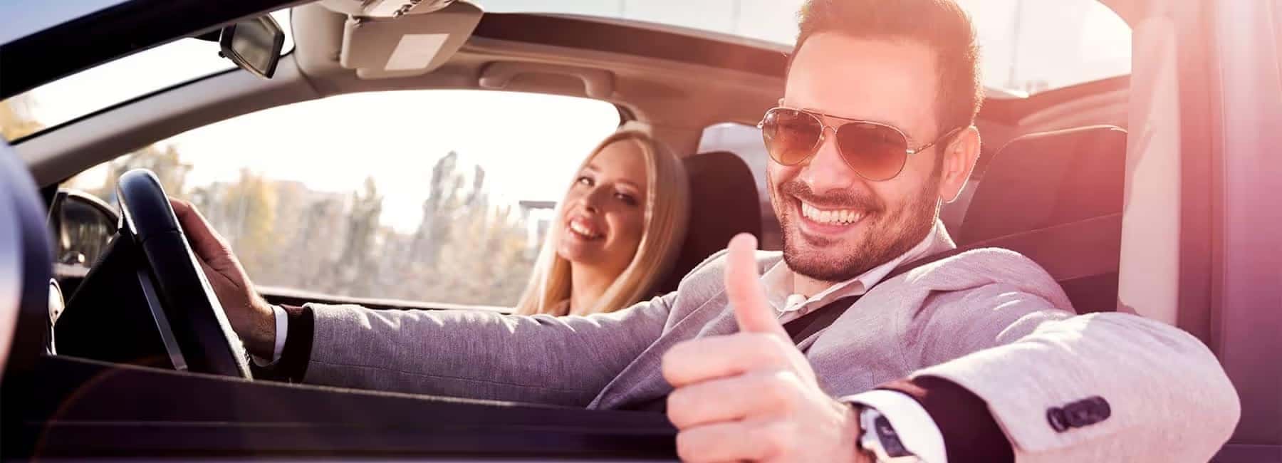man driving car giving thumbs up
