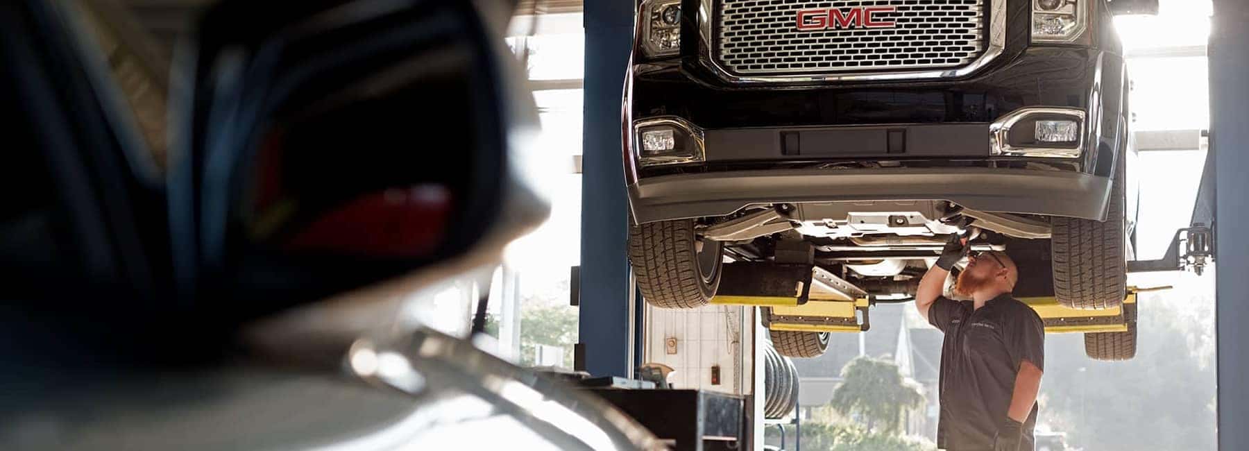 GMC Service Technician looking at underside of GMC vehicle
