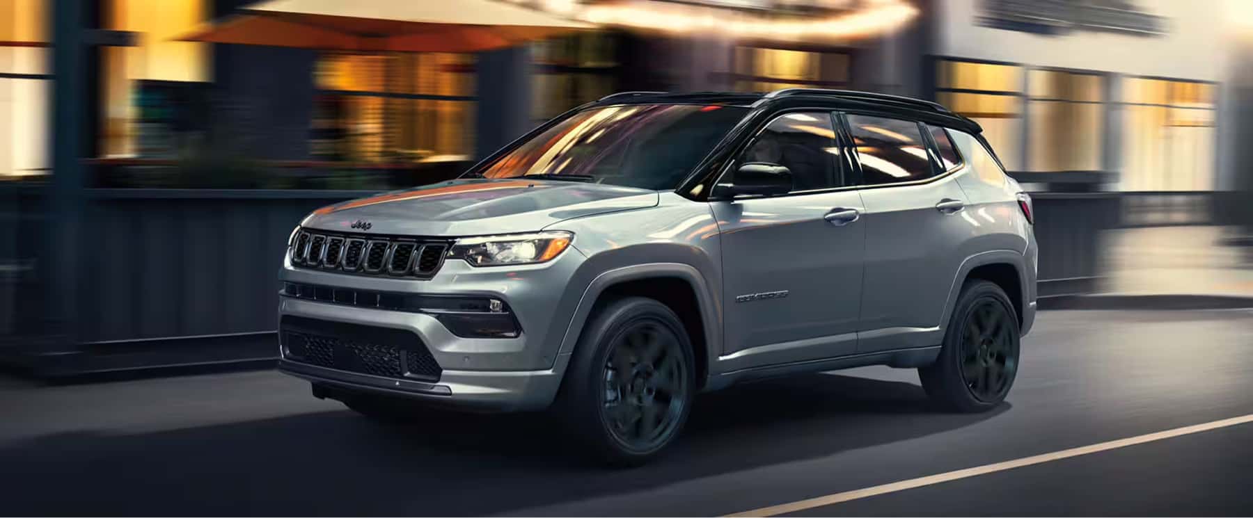 2025-Jeep-Compass-driving-past-a-downtown-cafe-patio