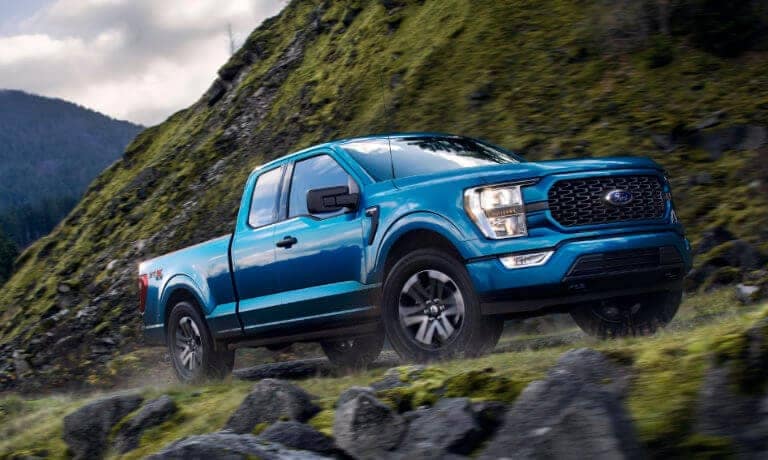 Blue Ford F-150 driving on a rocky hill
