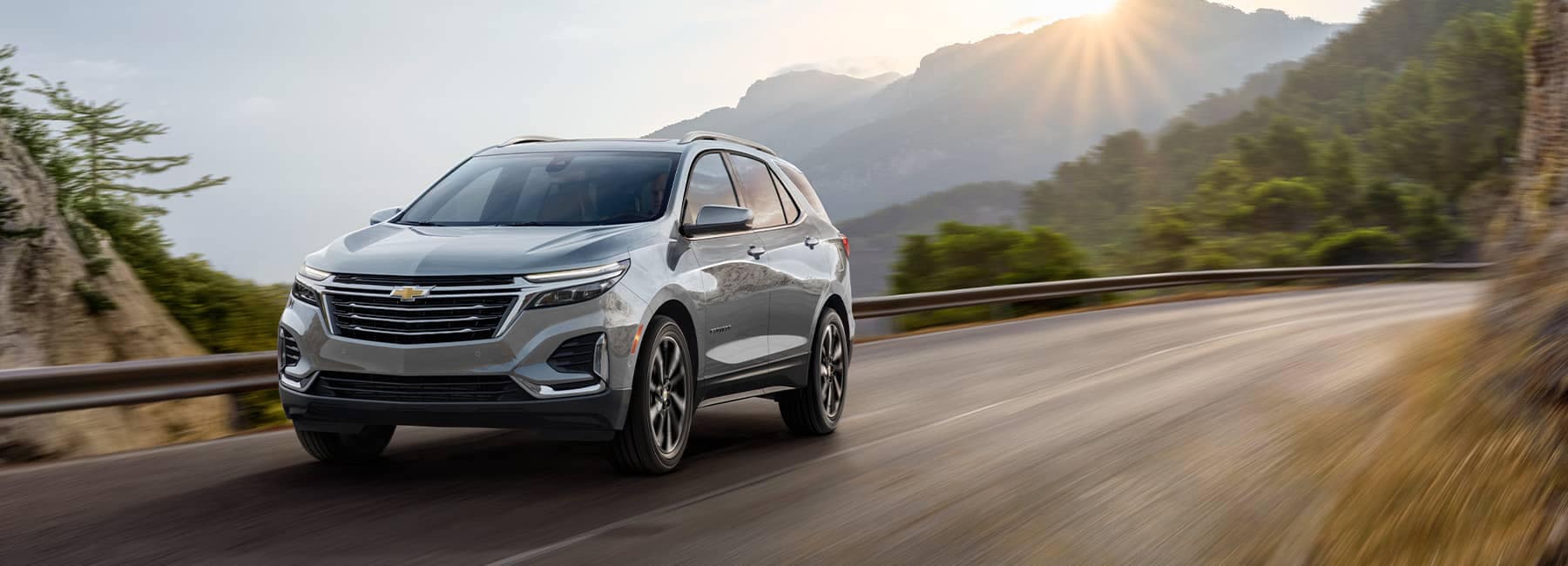 2023 Silver Chevrolet Equinox on a mountain road at sunrise