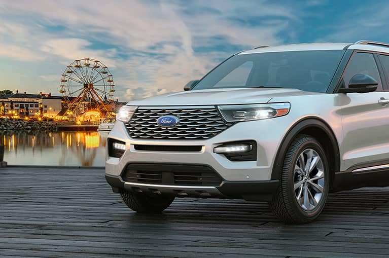 White 2021 Ford Explorer parked on a boardwalk with a ferris wheel in the background