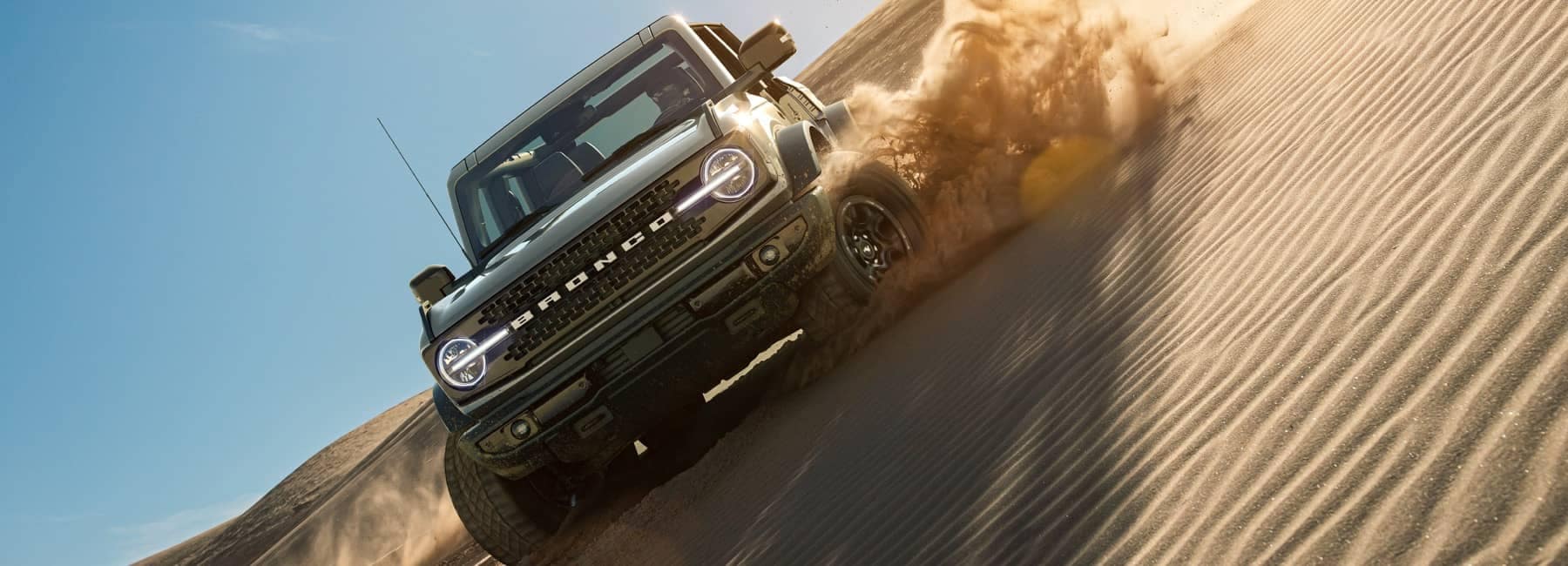 2021 Ford Bronco in Cactus Gray being driven on a sand dune